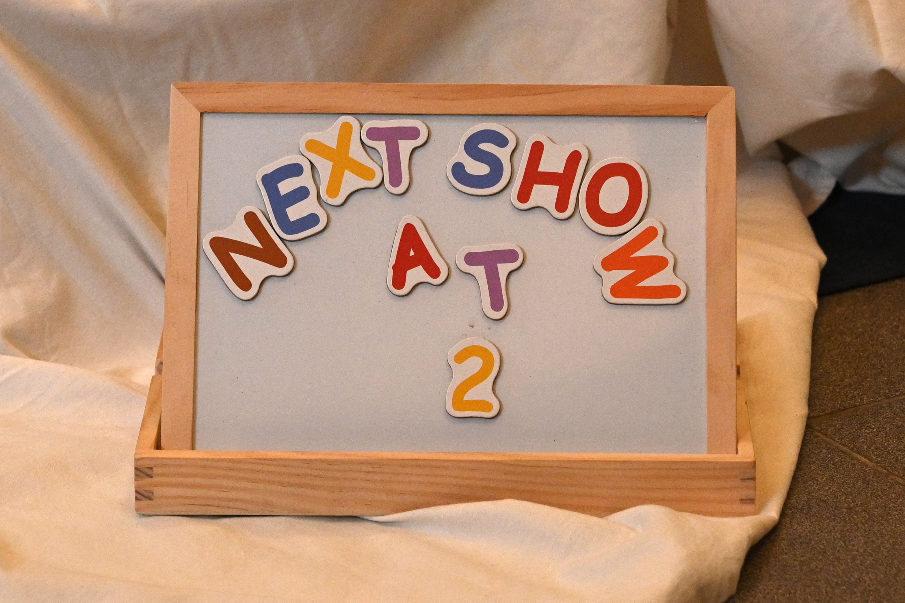 child's magnetic letters board witht he words 'next show
ow at 2' in magnetic letters