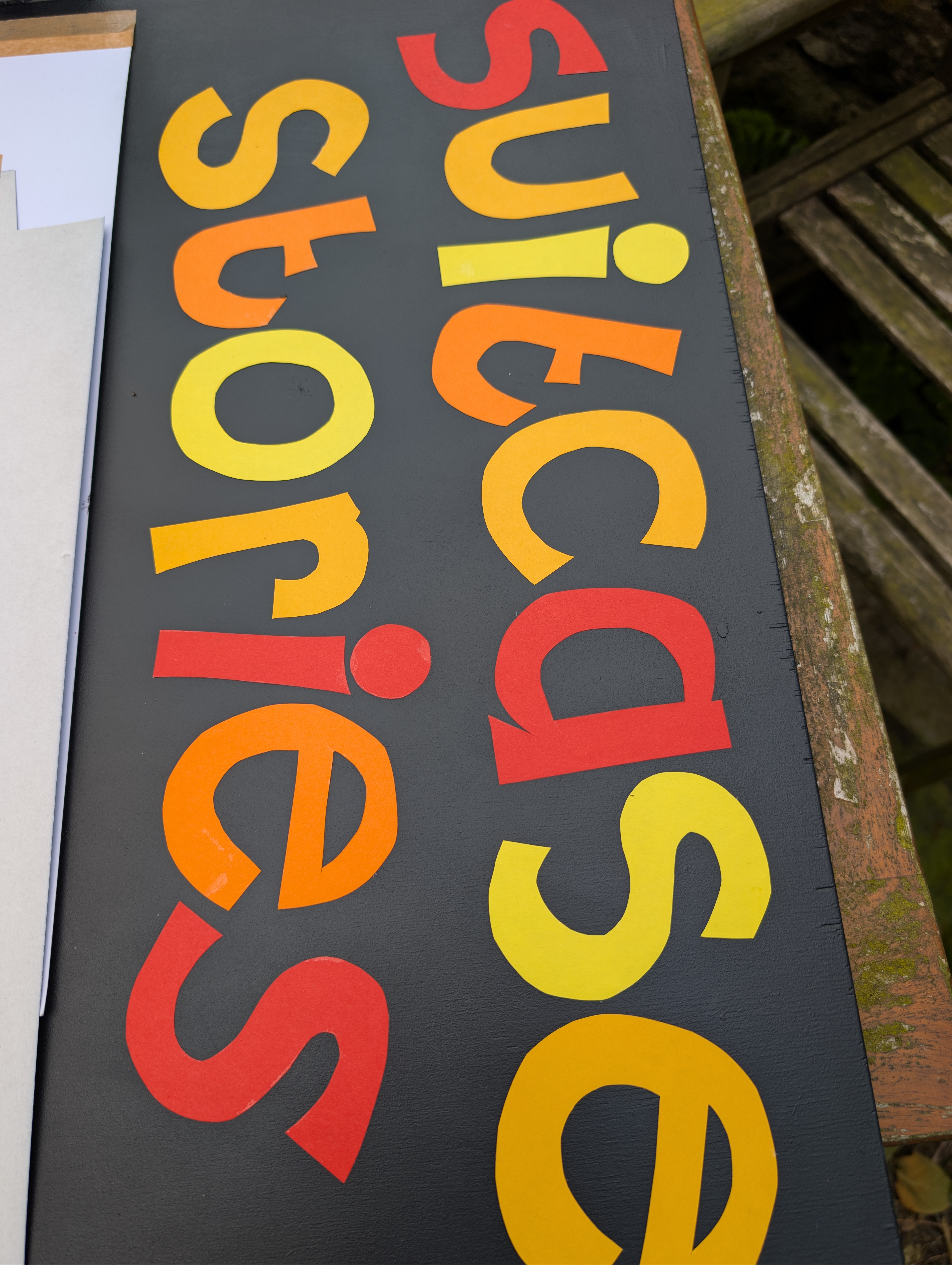 cl;ose up of cut otu letters on the board that say 'suitcase stories' in brightly 
coloured card on a blackboard background