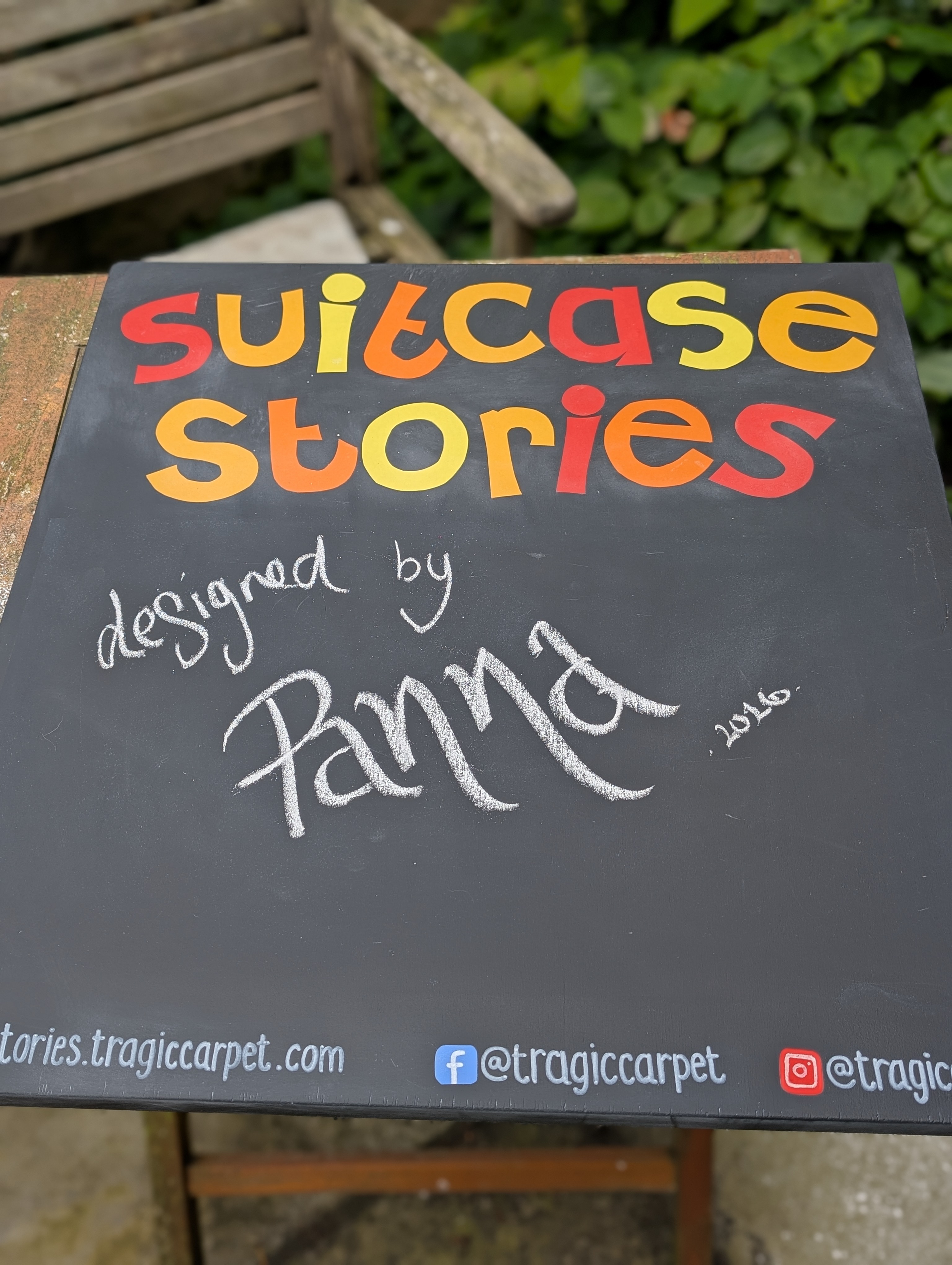 plackboard with bright letters saying Suitcase Stories and signed 'designed by Panna'