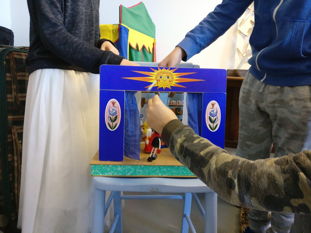 close up of childrens hands laying with puppets in a toy theatre