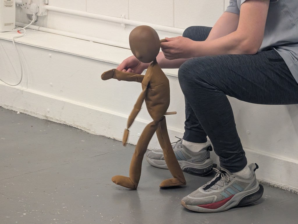 a tabletop puppet is being manipulated by the hands of a young person